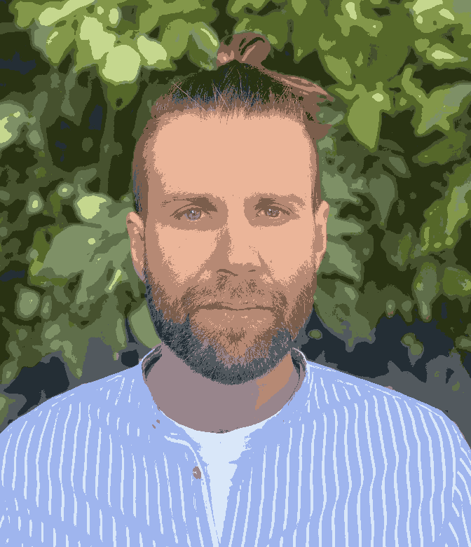 Portrait Foto von Achim mit hellblauem Hemd vor grüner Hecke Hintergrund 